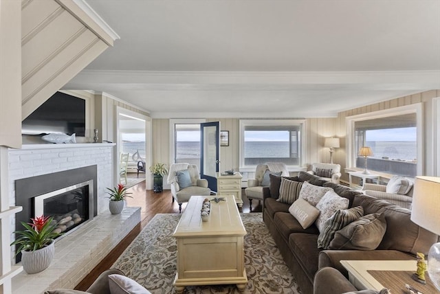 living room with light hardwood / wood-style floors, a water view, crown molding, and a brick fireplace