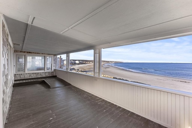 unfurnished sunroom featuring a water view and a beach view