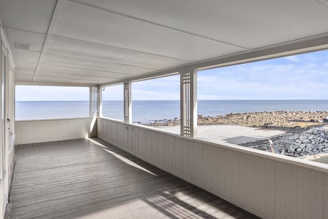 unfurnished sunroom featuring a water view and a beach view