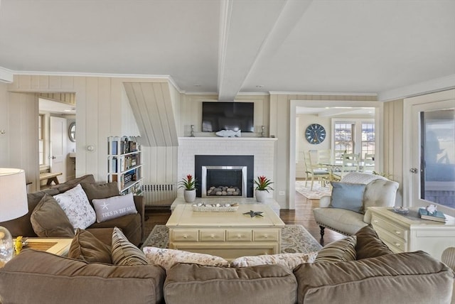 living room featuring dark wood-type flooring, radiator, crown molding, a brick fireplace, and beamed ceiling