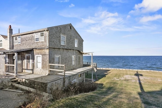 exterior space featuring a yard, a water view, and a beach view