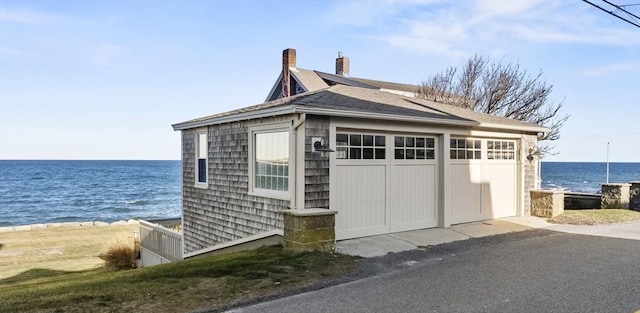 view of home's exterior with a water view, an outdoor structure, and a garage