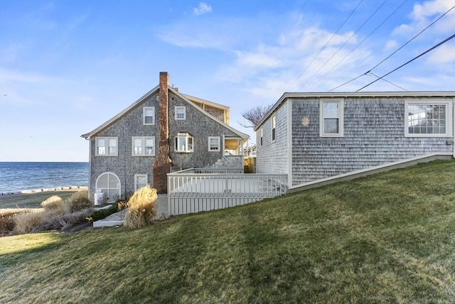 back of house featuring a lawn and a deck with water view