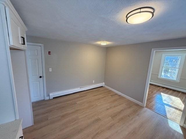 spare room with light hardwood / wood-style flooring, a textured ceiling, and baseboard heating