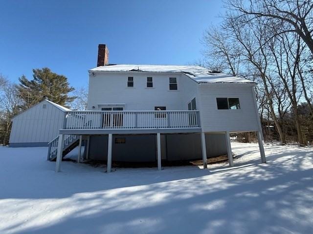 snow covered back of property featuring a wooden deck