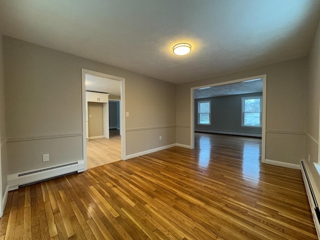 spare room featuring a baseboard radiator and light hardwood / wood-style floors