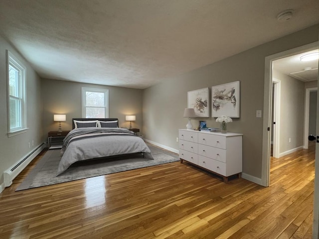 bedroom featuring hardwood / wood-style flooring and a baseboard heating unit