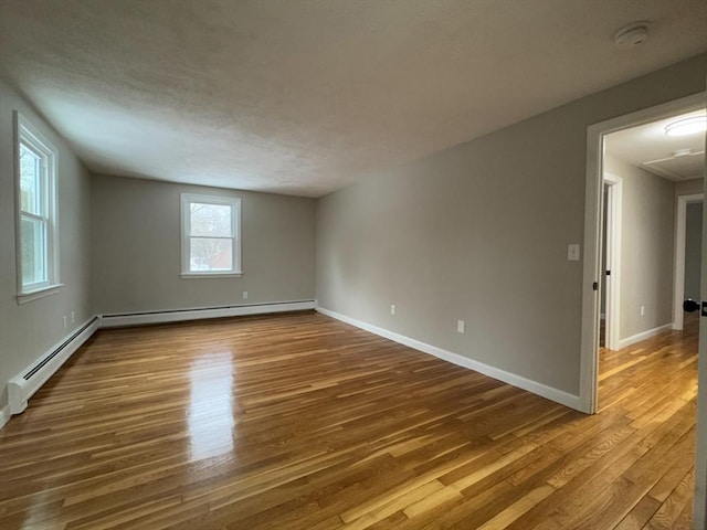 empty room with baseboard heating and hardwood / wood-style floors