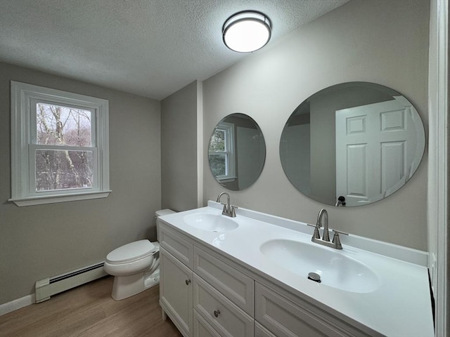 bathroom with hardwood / wood-style flooring, baseboard heating, vanity, a textured ceiling, and toilet