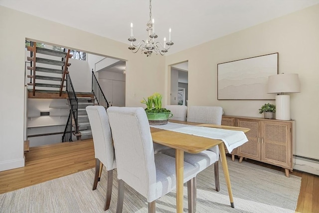 dining area with baseboards, an inviting chandelier, wood finished floors, and stairs