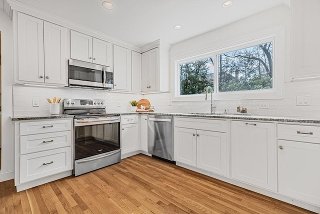 kitchen featuring light wood finished floors, white cabinetry, stainless steel appliances, and light stone counters