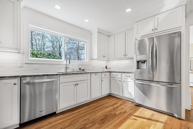 kitchen featuring white cabinets, stone countertops, stainless steel appliances, and a sink