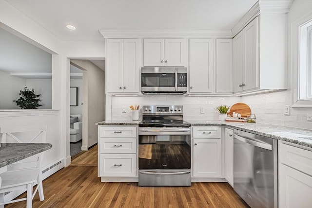 kitchen featuring light wood finished floors, white cabinets, appliances with stainless steel finishes, and light stone countertops