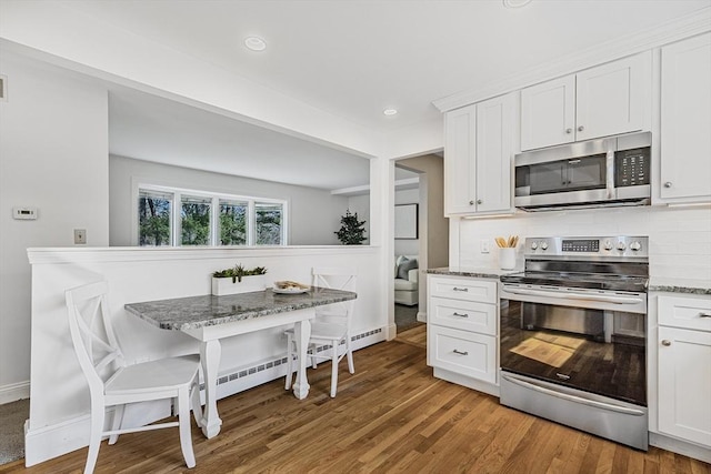 kitchen featuring tasteful backsplash, white cabinetry, appliances with stainless steel finishes, and breakfast area