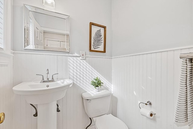 bathroom featuring a wainscoted wall and toilet