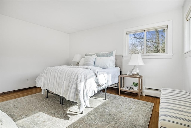 bedroom with a baseboard heating unit and wood finished floors