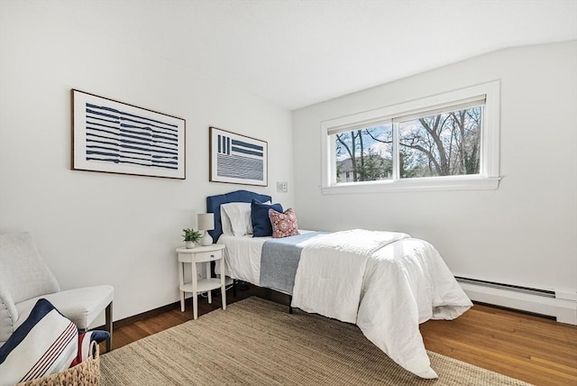 bedroom with a baseboard heating unit, baseboards, and wood finished floors