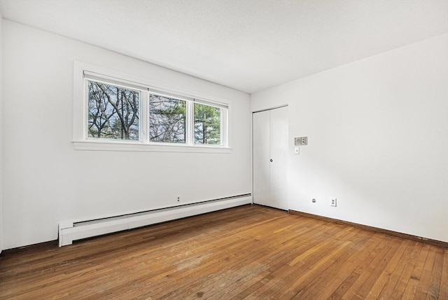 empty room with baseboards, baseboard heating, and hardwood / wood-style flooring