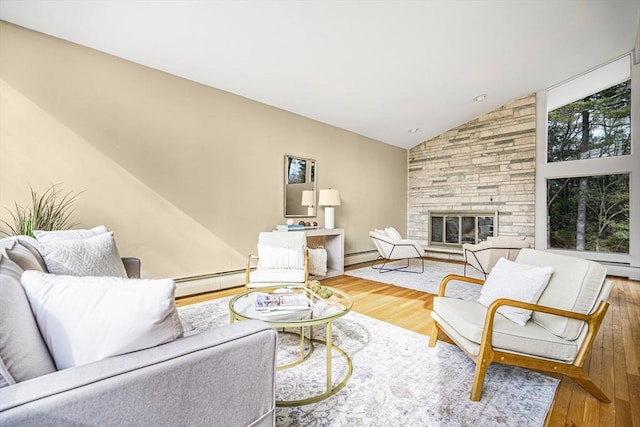 living area with a stone fireplace, lofted ceiling, wood finished floors, and a baseboard radiator