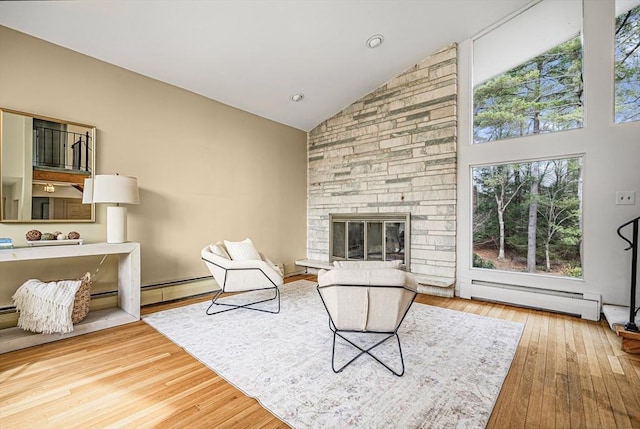 living room featuring high vaulted ceiling, a baseboard radiator, a fireplace, wood-type flooring, and a baseboard heating unit