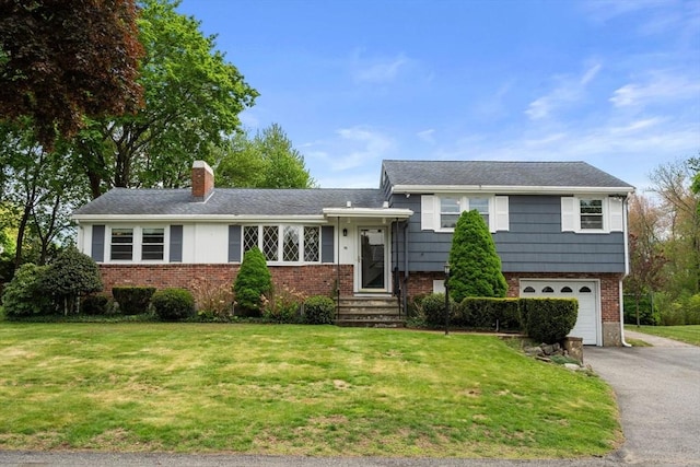 50 Thompson St, Dedham, MA 02026 - tri-level home with driveway, a chimney, a garage, a front yard, and brick siding