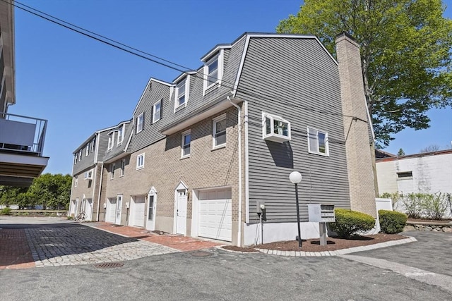 view of home's exterior featuring a garage, a balcony, and a chimney