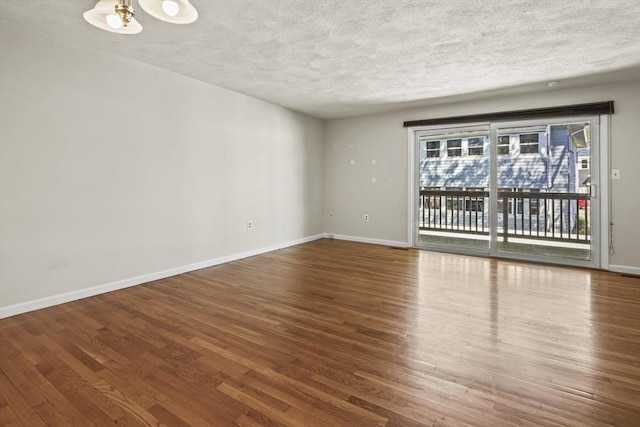 spare room with baseboards, a textured ceiling, and wood finished floors