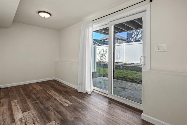 spare room with baseboards and dark wood-style floors