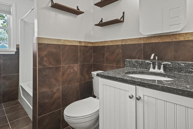 full bath featuring tile patterned flooring, vanity, toilet, a wainscoted wall, and tile walls