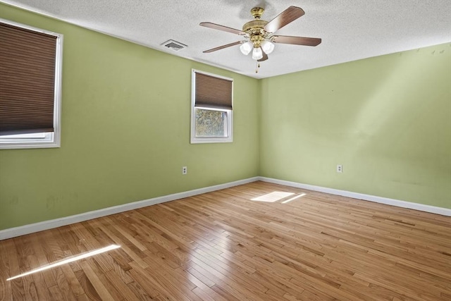 unfurnished room with visible vents, wood finished floors, baseboards, a textured ceiling, and a ceiling fan