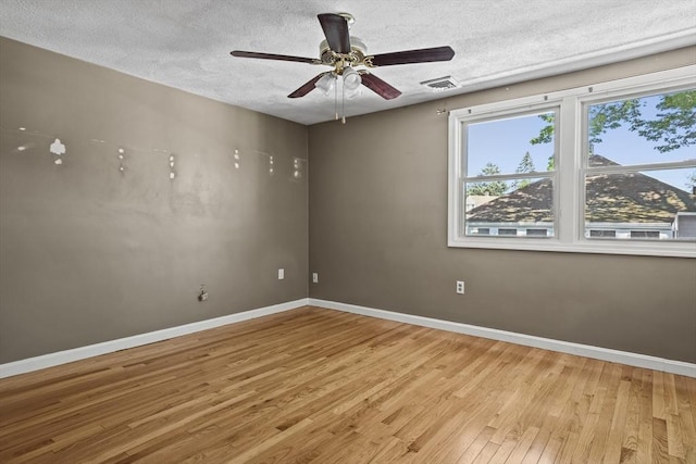 spare room featuring baseboards, ceiling fan, a textured ceiling, and light wood-style flooring