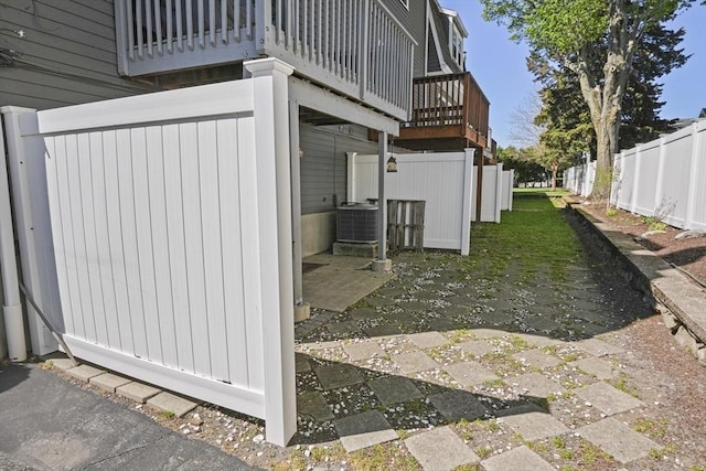 view of side of home with central air condition unit, fence, and a wooden deck