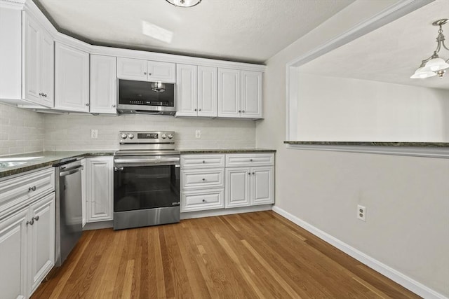 kitchen with white cabinetry, appliances with stainless steel finishes, decorative backsplash, and wood finished floors
