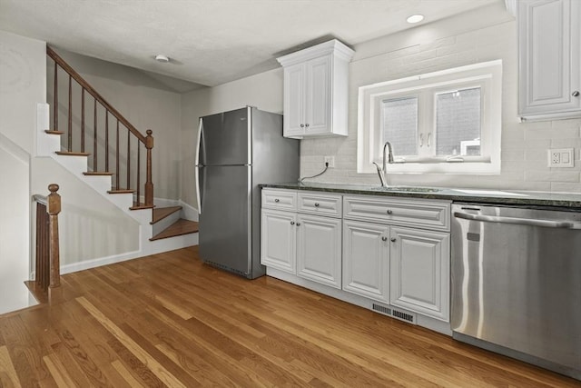 kitchen featuring visible vents, a sink, light wood finished floors, stainless steel appliances, and white cabinetry