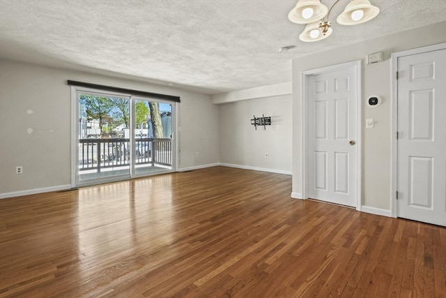 unfurnished room with baseboards, a textured ceiling, and wood finished floors