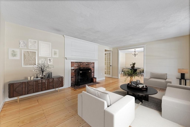 living room featuring a brick fireplace, a textured ceiling, and light wood-type flooring