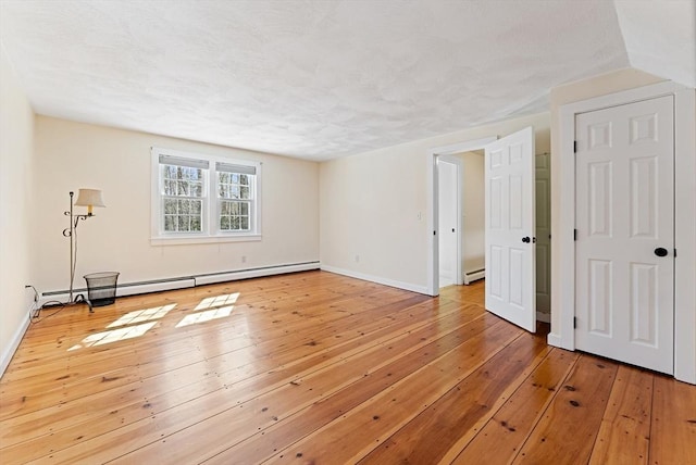 spare room featuring wood-type flooring, baseboards, baseboard heating, and a textured ceiling