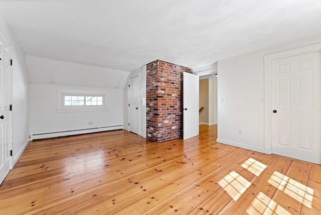 interior space featuring vaulted ceiling, baseboards, light wood-style floors, and a baseboard radiator