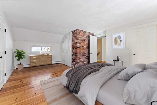 bedroom featuring a baseboard heating unit, light wood-style floors, baseboard heating, and vaulted ceiling