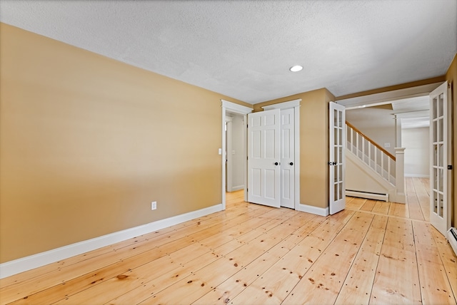 spare room with stairs, hardwood / wood-style flooring, baseboards, and a baseboard radiator