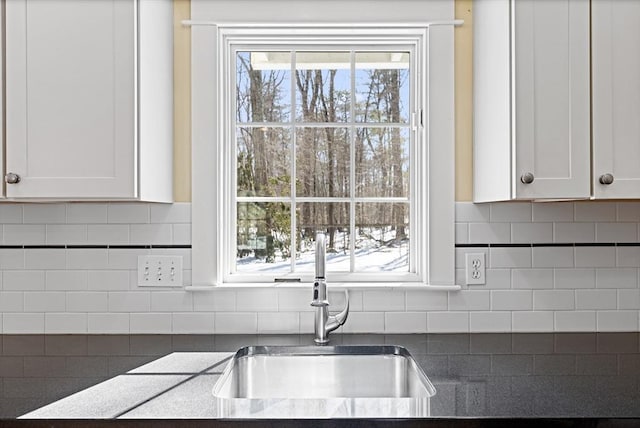 kitchen with a sink, tasteful backsplash, and white cabinets