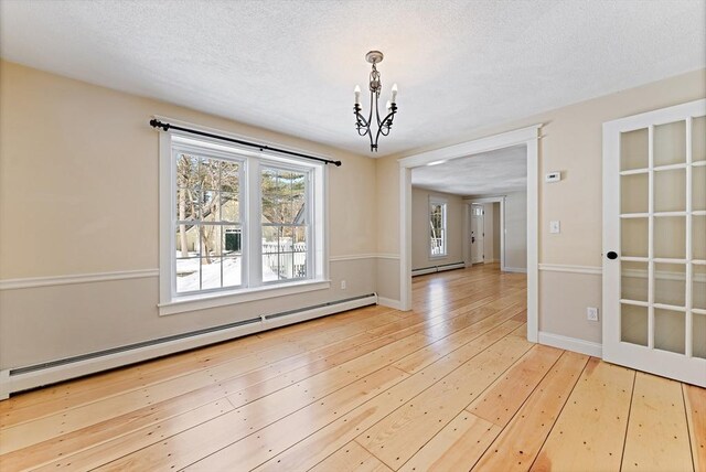 unfurnished room featuring a textured ceiling, a notable chandelier, wood-type flooring, and a baseboard radiator