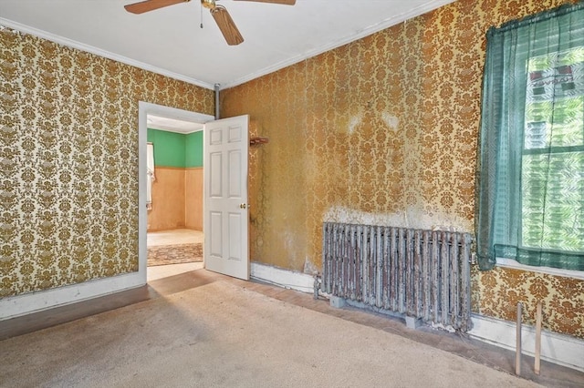 empty room featuring radiator, crown molding, a ceiling fan, and wallpapered walls