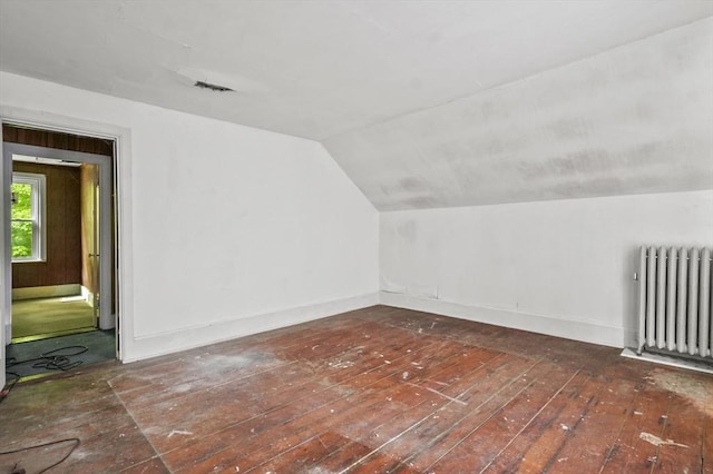 additional living space featuring radiator, lofted ceiling, baseboards, and hardwood / wood-style floors