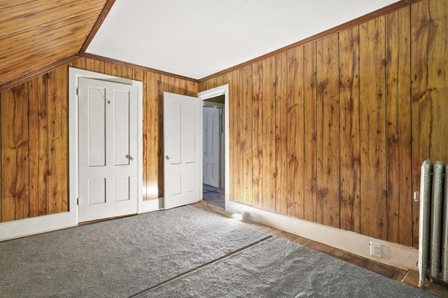 bonus room with wooden walls, radiator, and vaulted ceiling