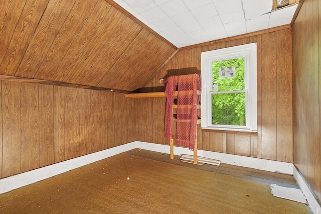 bonus room with wooden walls and vaulted ceiling