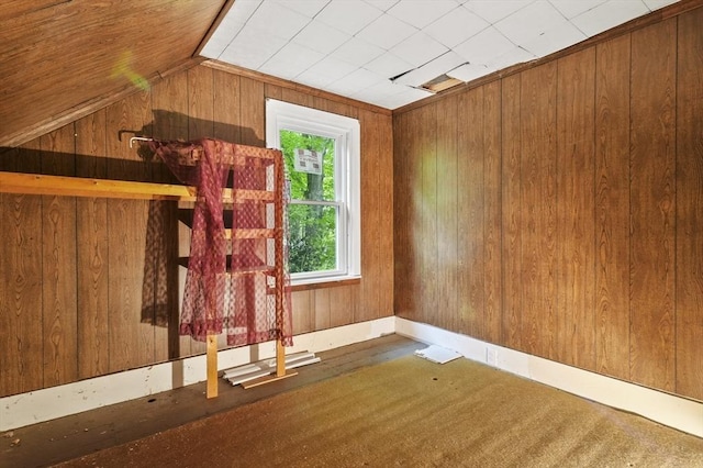 spare room featuring wood walls and lofted ceiling