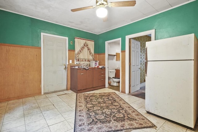 foyer entrance with a ceiling fan and wainscoting
