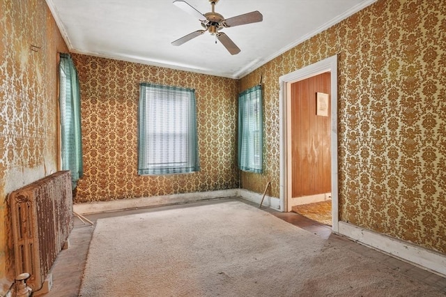 empty room with crown molding, wallpapered walls, ceiling fan, baseboards, and radiator heating unit