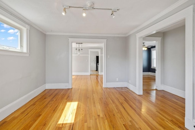 spare room with crown molding, track lighting, baseboards, light wood-type flooring, and ceiling fan with notable chandelier
